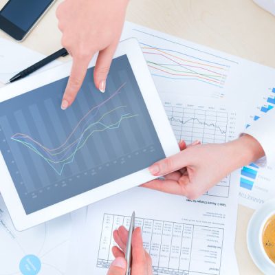 Businessman discussing with financial analyst business development strategy project and using modern digital tablet with chart on a screen. Top view photoshoot.